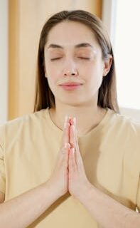 Calm woman practicing meditation indoors with eyes closed, exuding peacefulness.
