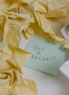 Close-up of a sticky note with 'Take a Break' surrounded by crumpled papers, suggesting a pause.